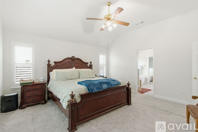 A bedroom with a large bed, a ceiling fan, and a nightstand with a speaker.