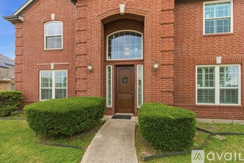 A red brick house with a brown door and two windows.