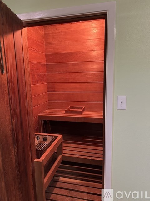 A wooden sauna with a bench and control panel.