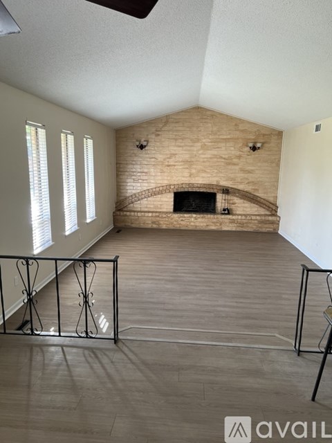 A room with a brick fireplace and a ceiling fan.