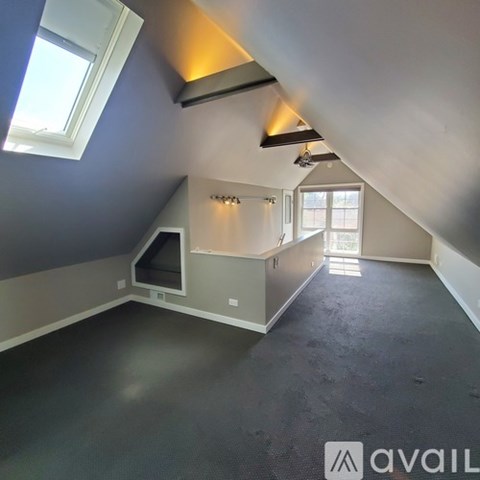 A spacious attic room with a skylight and a built-in desk.