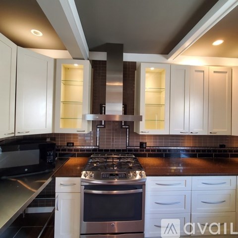 A modern kitchen with white cabinets and a stainless steel stove top.
