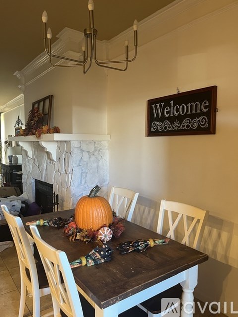 A dining room with a wooden table and chairs, a fireplace, and a "Welcome" sign.