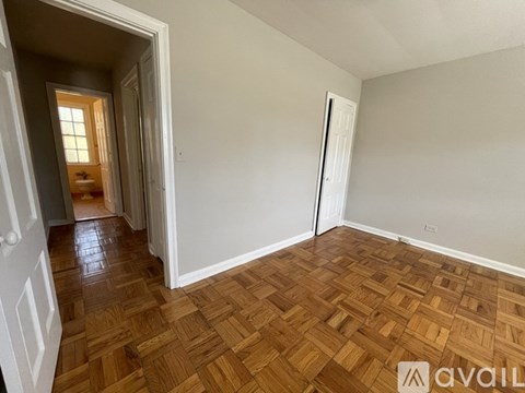 A room with wooden flooring and white walls is available for rent.