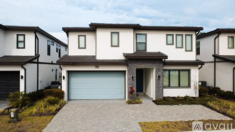 A modern house with a large driveway and garage doors.