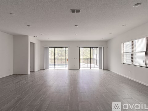 A spacious room with wooden flooring and large windows.
