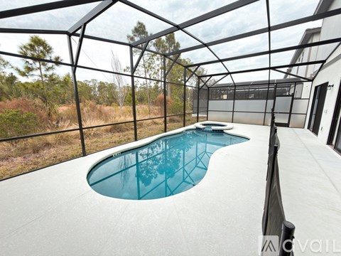 A pool inside a glass enclosure with trees in the background.