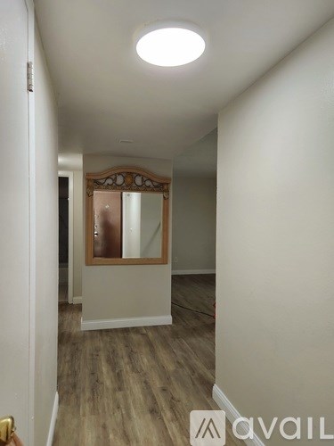 A hallway with a wooden floor and a mirror on the wall.