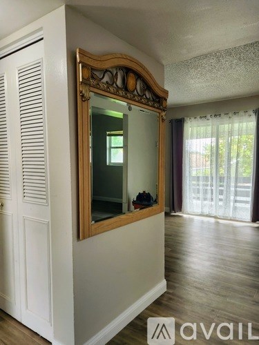 A large mirror with a wooden frame hangs on a white wall.