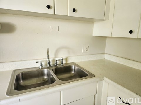 A kitchen with two sinks and white cabinets.