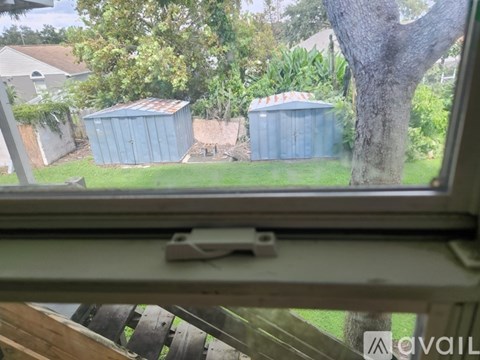 A view from a window looking out at two blue sheds in a yard.
