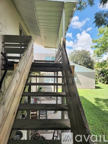 A wooden staircase with a metal railing leads up to a balcony.