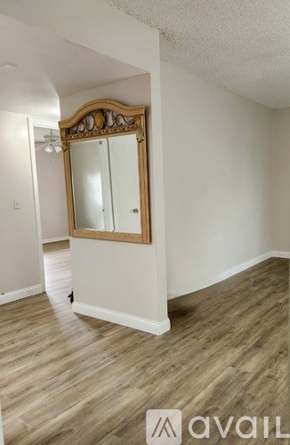 A large mirror with a wooden frame is on a stand in a room with wooden flooring.