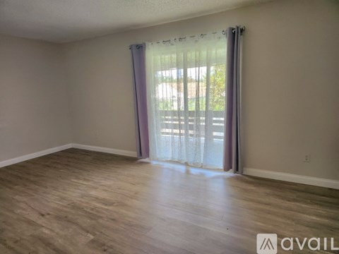 A room with wooden flooring and a window with curtains.