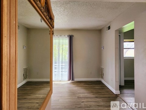 A room with wooden floors and a window with curtains.
