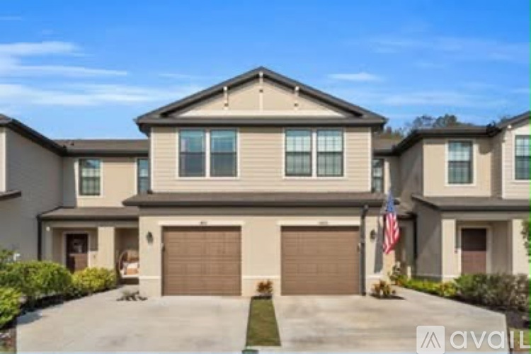 A large, two-story house with a garage and a driveway is for sale.