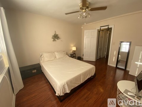 A bedroom with a bed, a ceiling fan, and a plant on the wall.