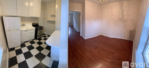 A black and white checkered floor in a kitchen with white cabinets and a white fridge.