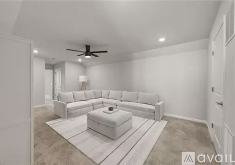 A spacious living room with a white sofa set and a rug.