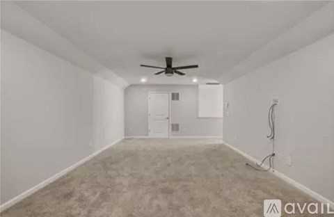 A spacious room with a ceiling fan and carpeted floor.