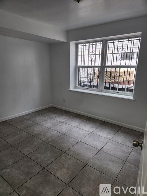 A room with a tiled floor and a window with bars.