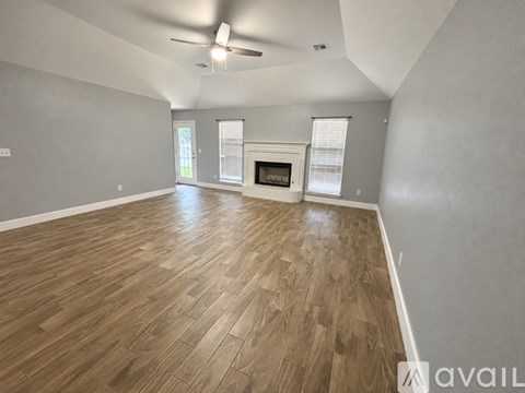 A spacious room with wooden flooring and a fireplace.