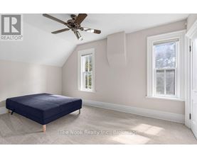 A bedroom with a bed, a ceiling fan, and two windows.