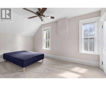 A bedroom with a bed, a ceiling fan, and two windows.