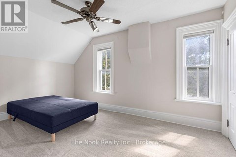 A bedroom with a bed, a ceiling fan, and two windows.