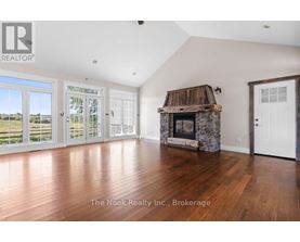 A spacious room with a stone fireplace and wooden flooring.