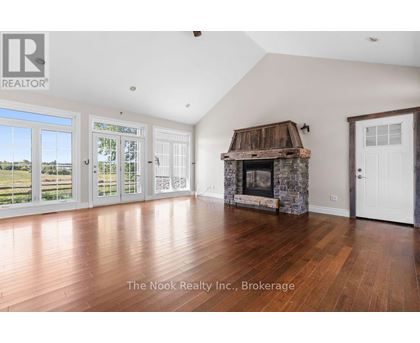 A spacious room with a stone fireplace and wooden flooring.