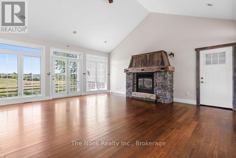 A spacious room with a stone fireplace and wooden flooring.