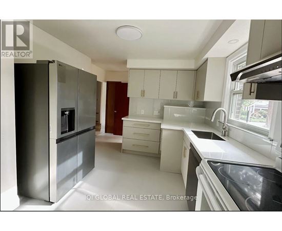 A modern kitchen with white cabinets and a stainless steel refrigerator.