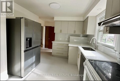 A modern kitchen with white cabinets and a stainless steel refrigerator.