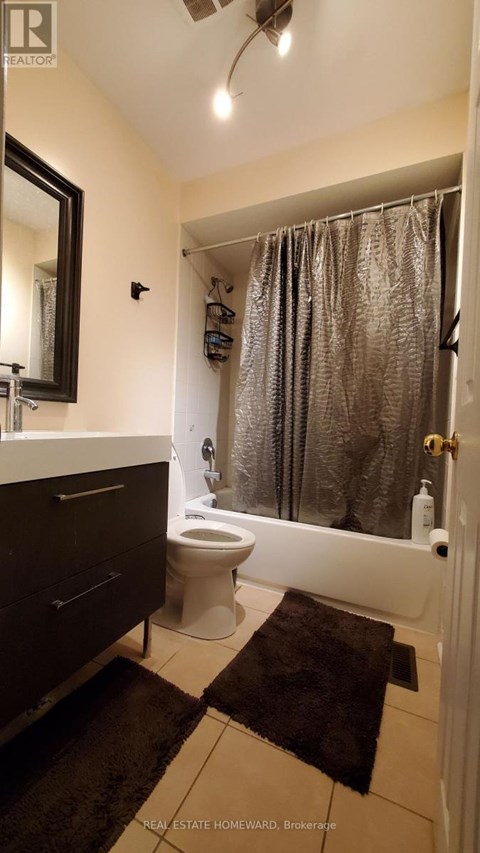 A bathroom with a toilet, sink, and shower curtain.