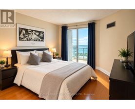 A bedroom with a large bed, a painting on the wall, and a view of the ocean through the window.