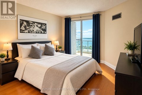 A bedroom with a large bed, a painting on the wall, and a view of the ocean through the window.