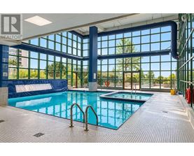 A large indoor swimming pool with a blue tiled floor and a glass wall.