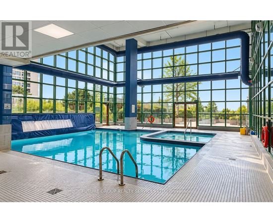 A large indoor swimming pool with a blue tiled floor and a glass wall.