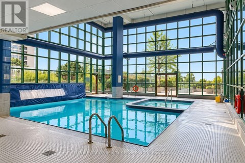 A large indoor swimming pool with a blue tiled floor and a glass wall.