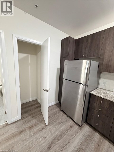 A kitchen with a refrigerator and wooden cabinets.