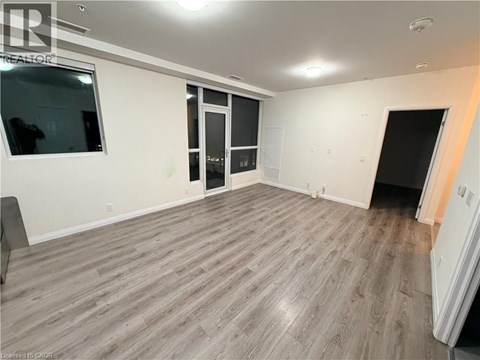 A spacious room with wooden flooring and white walls.