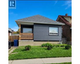 A house with a grey siding and a brown wooden fence.