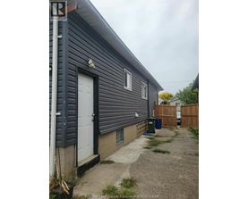 A grey house with a white door and a small garden.
