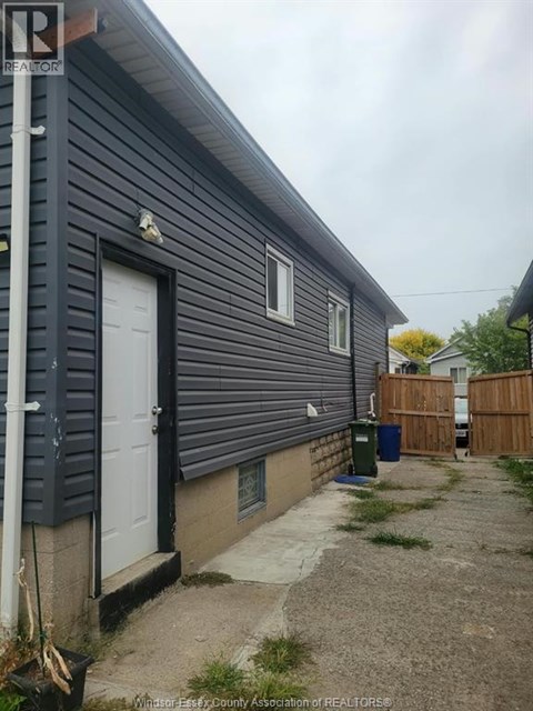 A grey house with a white door and a small garden.