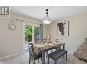 A dining room with a table set for two and a clock on the wall.