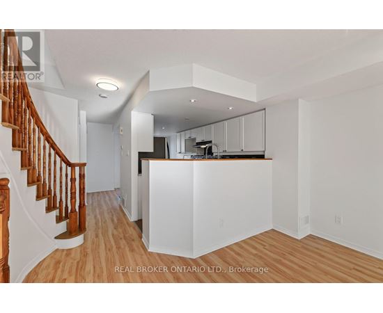 A spacious kitchen with white cabinets and a wooden staircase.