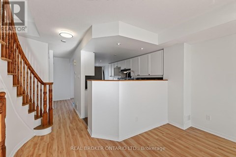 A spacious kitchen with white cabinets and a wooden staircase.