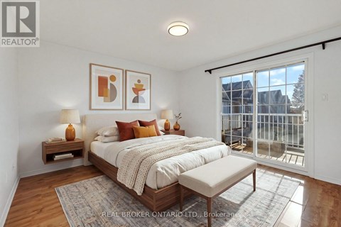 A bedroom with a large bed and a balcony overlooking a city.
