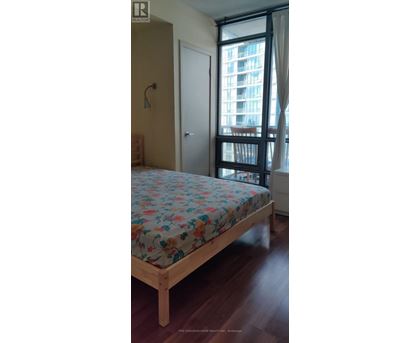 A bedroom with a large bed and a window overlooking a building.